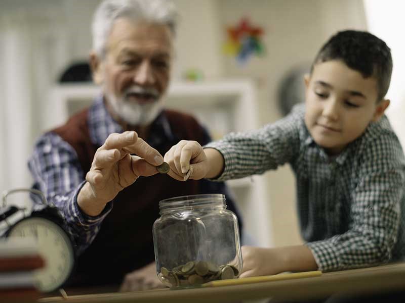 Image of older man and young boy putting money in jar